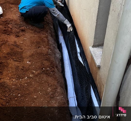 אדם מתקין יריעת איטום על קיר חיצוני